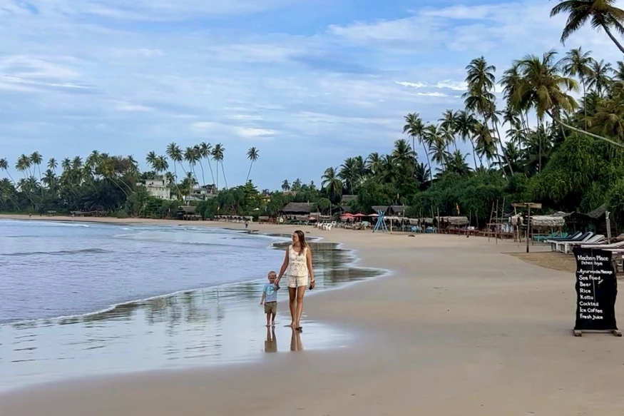 Walking along Dickwella beach in Sri Lanka, with gentle waves and palm trees.